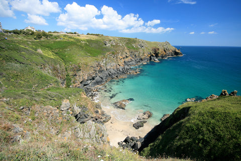 A photo of Housel Bay beach, a small snady beach below the cliffs with a turquoise sea. Remote and beautiful. Taken from Friendly Guides Lizard Guidebook.