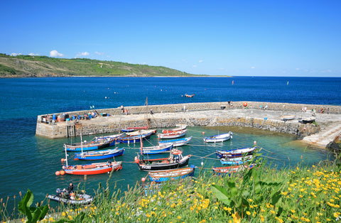 Coverack Harbour in the sunshine. A stone harbour are encloses a colourful collection of small boats.