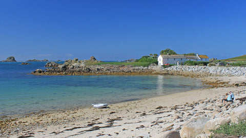 A couple sit on the beach looking over Great Par