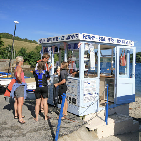 Photo from Friendly Guides Helford Guidebook of people buying ice creams at the ferry kiosk for Helford River Boats at Helford Passage