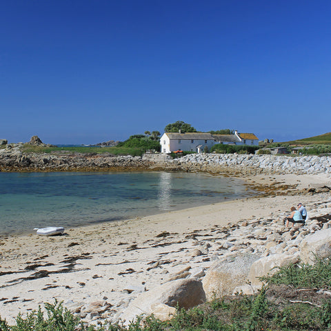 Photo from Friendly Guides Isles of Scilly Guidebook showing people sitting on the beach at Great Par near the Hell Bay Hotel on Bryher, Isles of Scilly.