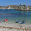 Photo from Friendly Guides Isles of Scilly Guidebook showing boats in Kitchen Porth on Bryher, Isles of Scilly. Looking over New Grimsby Sound to Cromwell's Castle and King Charles' Castle on Tresco.