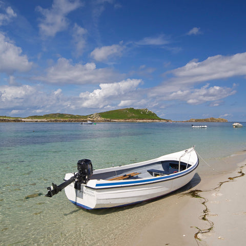 Photo from Friendly Guides Isles of Scilly Guidebook showing a boat at The Porth, Lowertown on St Martin's, Isles of Scilly. In the background Great Hill on Tean.